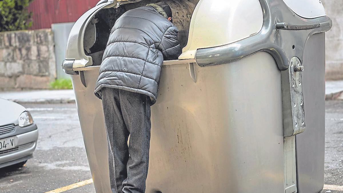 Una persona buscant menjar en un contenidor, en una imatge de recurs.