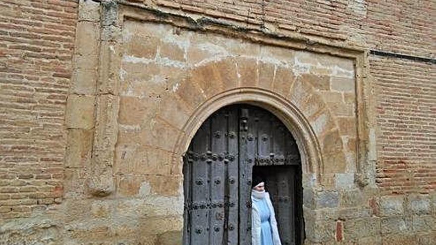 Una religiosa del convento se asoma por la antigua puerta de la iglesia que será restaurada.