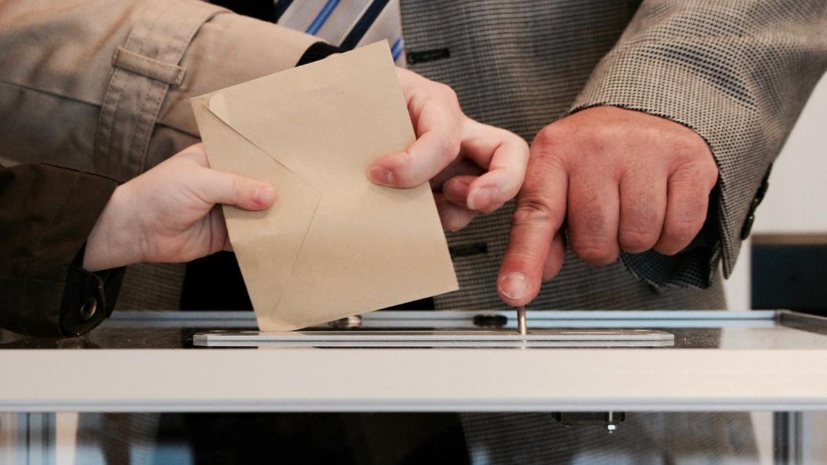 Electores depositan el sobre con el voto en una urna.