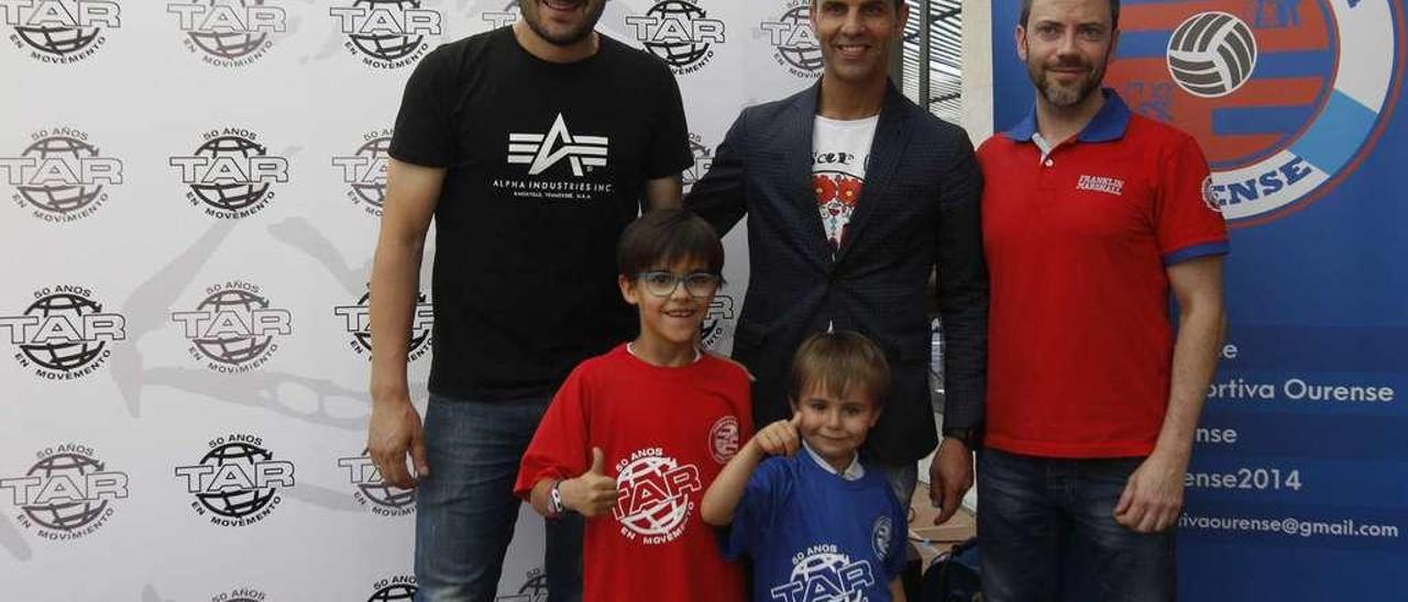 Fernando Currás, Juan López, gerente de TAR, y Modesto García posan con dos pequeños que lucen las camisetas de la escuela. // J. Regal
