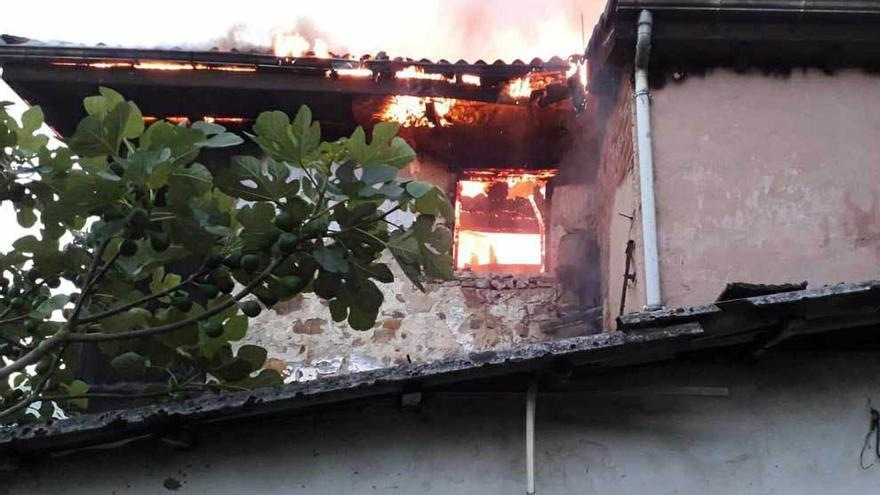 El fuego saliendo de una de las ventanas de la vivienda incendiada en Laviana.