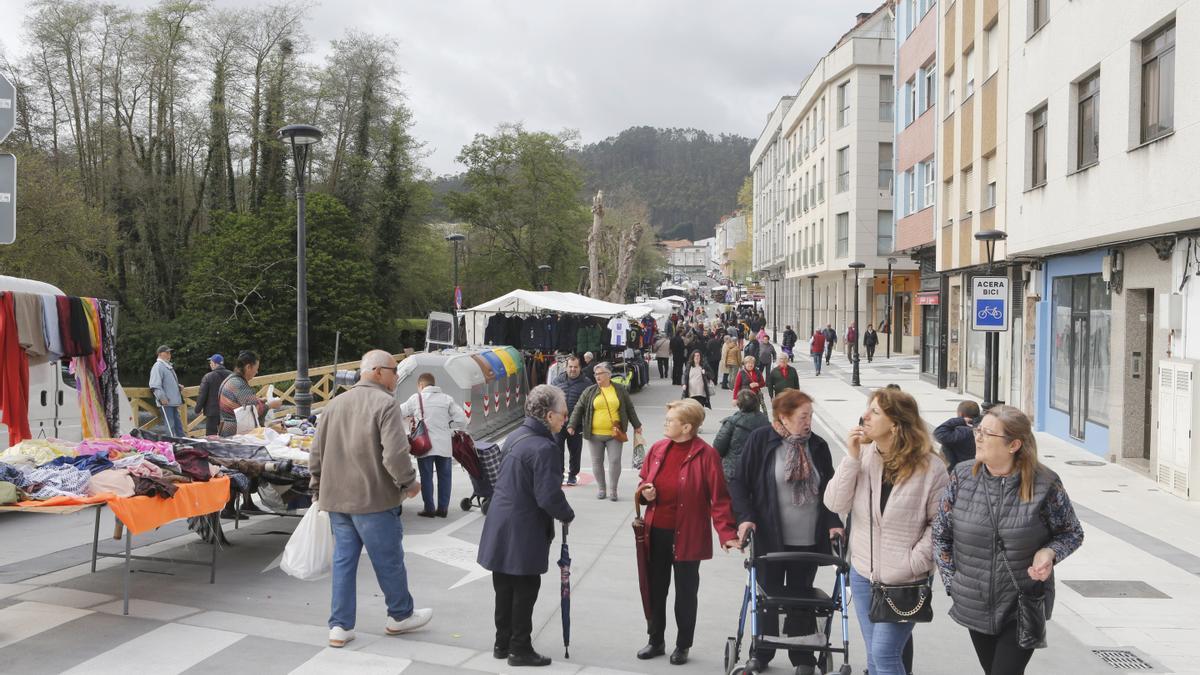 Clientas comprando productos de alimentación y ramos de flores a los vendedores instalados en la plaza do Balneario.