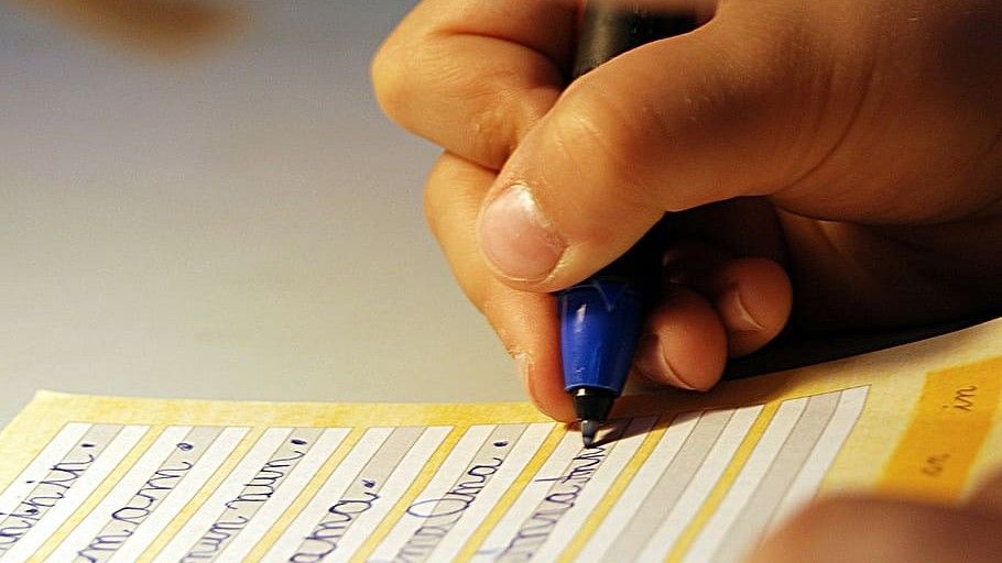 Un niño escribe en un cuaderno de caligrafía