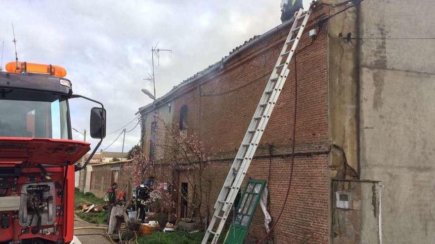 Los bomberos de Toro trabajan en la extinción y desescombro en el interior de la vivienda siniestrada, cuyo tejado aparece a la derecha totalmente calcinado.