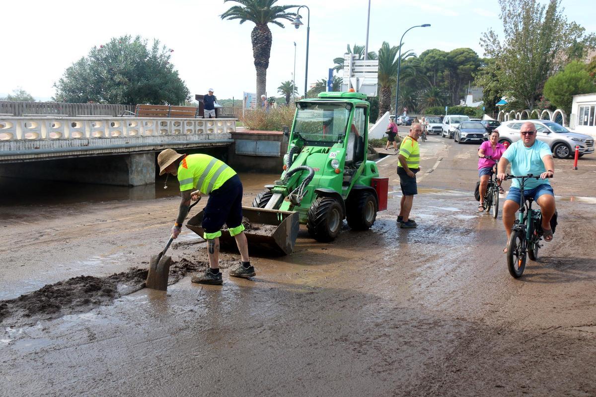 Treballadors de les brigades municipals netejant el fang en una rotonda a tocar de la platja de l'Estartit