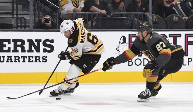 Brad Marchand # 63 de los Boston Bruins pasa el disco detrás de él bajo la presión de Shea Theodore # 27 de Vegas Golden Knights en el primer período de su juego en el T-Mobile Arena en Las Vegas, Nevada.