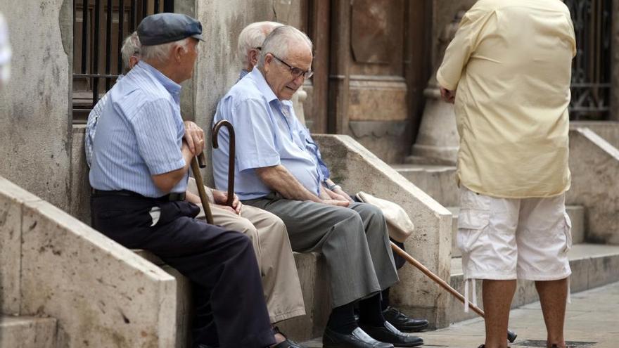 Un grupo de personas mayores, sentados en una plaza en Valencia.