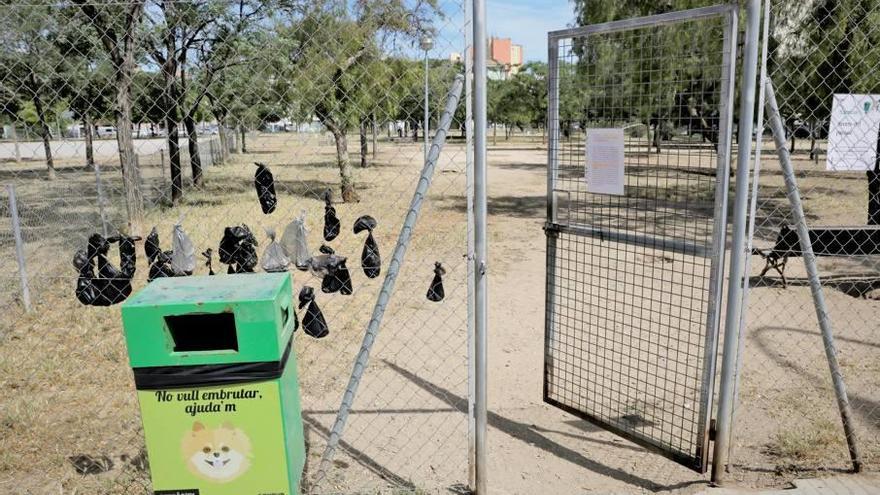 Una veintena de bolsas con excrementos de perro cuelgan de la valla junto a la entrada al parque.