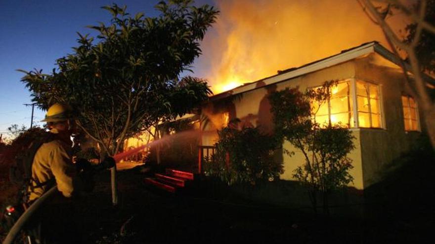 Un bombero intenta apagar el fuego de una vivienda