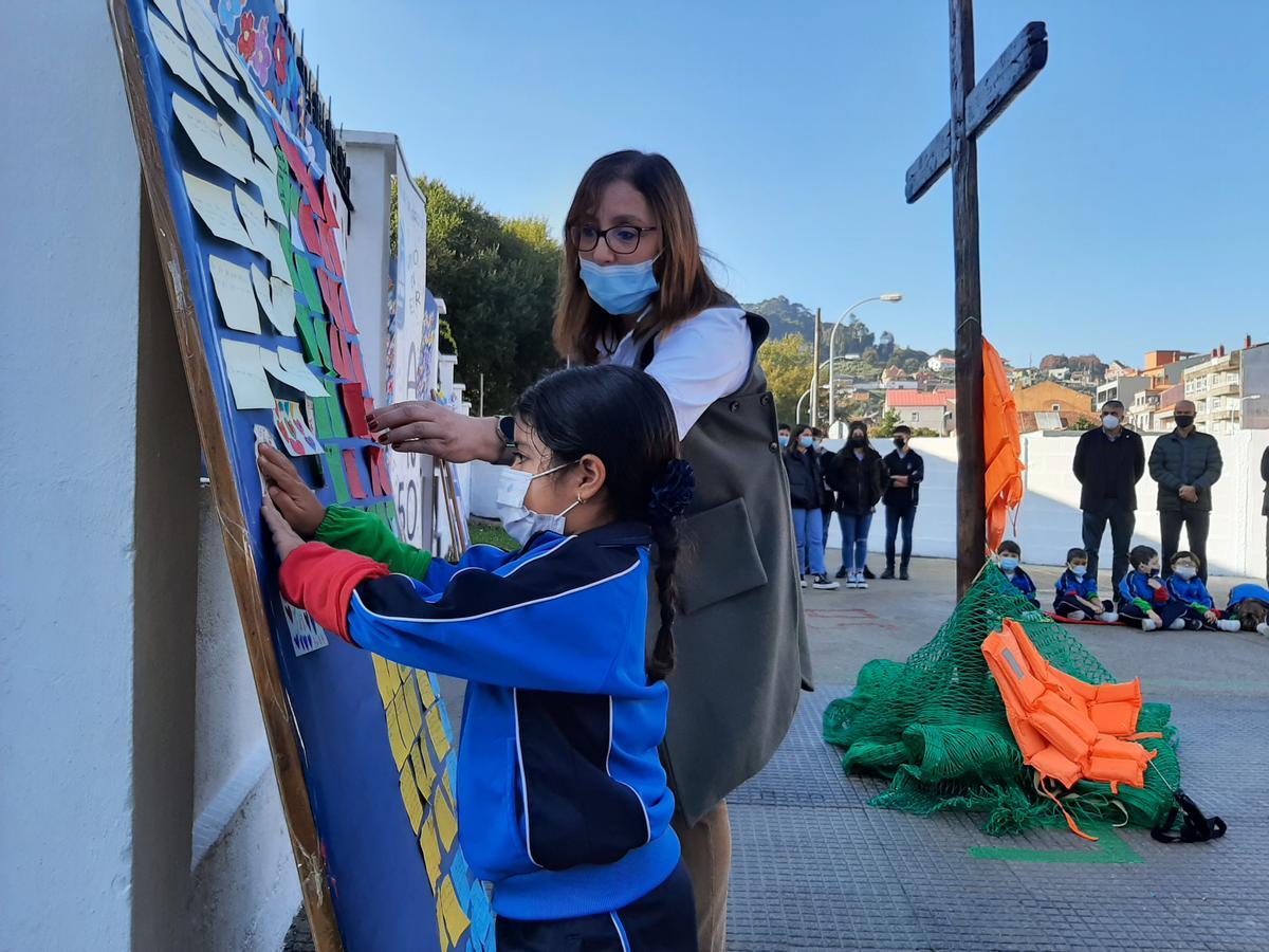 Una alumna pega una tarjeta con sus deseos, con la cruz al fondo.