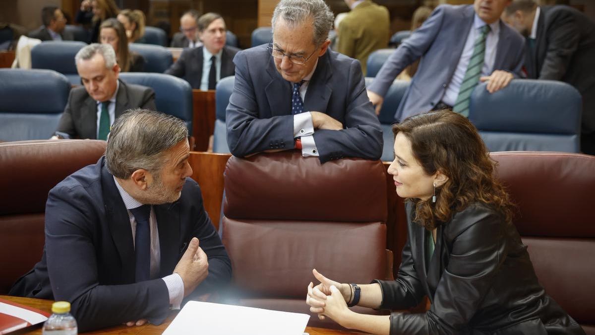 Isabel Díaz Ayuso habla con Enrique López en la Asamblea de Madrid ante la mirada de Enrique Ossorio.
