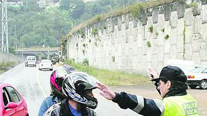 Una policía local de Langreo da instrucciones a un motorista en un cruce.