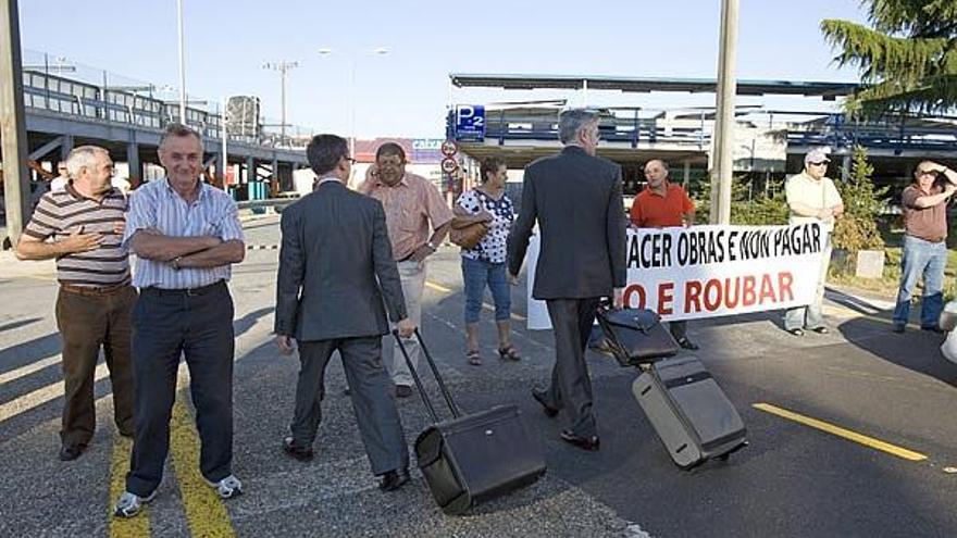Dos viajeros franquean la fila de manifestantes de Cabral para acceder a la terminal viguesa y coger sus vuelos.