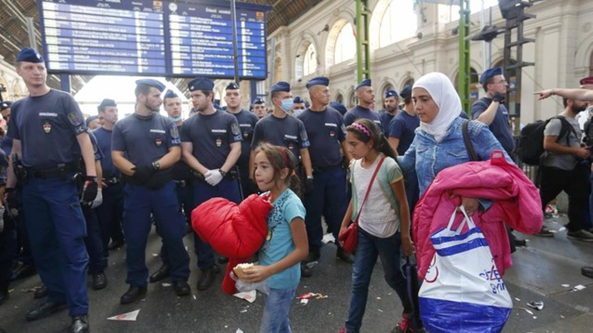 Una familia de refugiados deja la estación más importante de este de Budapest, después de que la policía la cerrara impidiédoles el paso con una valla humana.