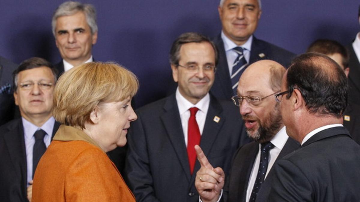 El presidente del Parlamento Europeo, Martin Schulz, se dirige a la cancillera alemana, Angela Merkel, ante el presidente francés, François Hollande (de espaldas), durante la foto de familia, el jueves en Bruselas.