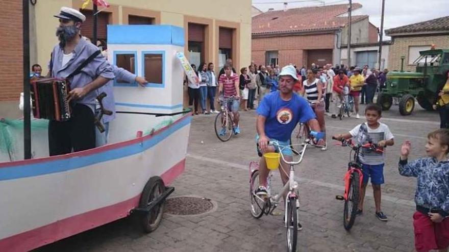 Los personajes de Verano Azul siguen con sus bicicletas la carroza del barco de Chanquete, que vuelve a tocar el acordeón en Arcenillas.