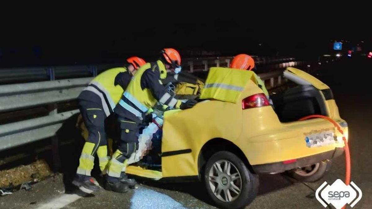 Los bomberos, junto al coche siniestrado.