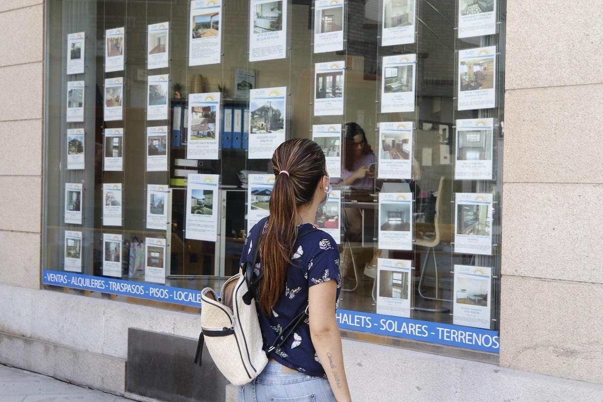 Una joven mira los anuncios de una inmobiliaria.