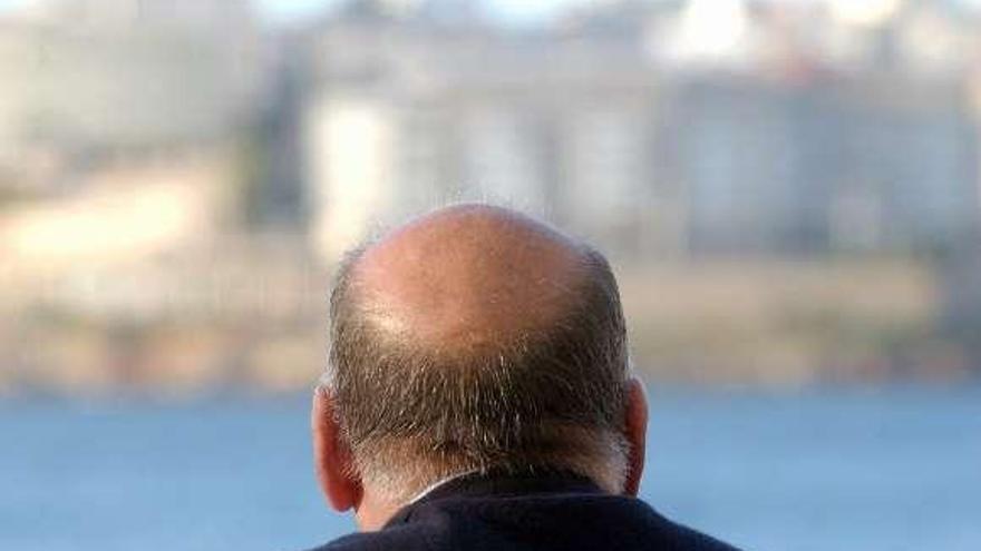 Un hombre calvo mira el mar en el litoral gallego.  // Juan Varela
