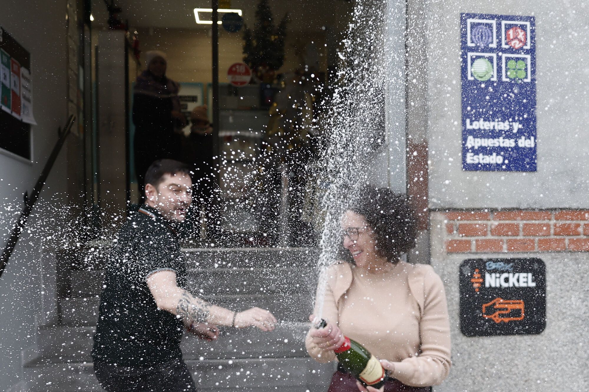 MADRID, 06/01/2025.- Beatriz Rodríguez, dueña de la administración de San Sebastián de los Reyes que ha vendido parte del número 06.766 agraciado con el segundo premio, abre una botella para celebralo. EFE/Sergio Pérez