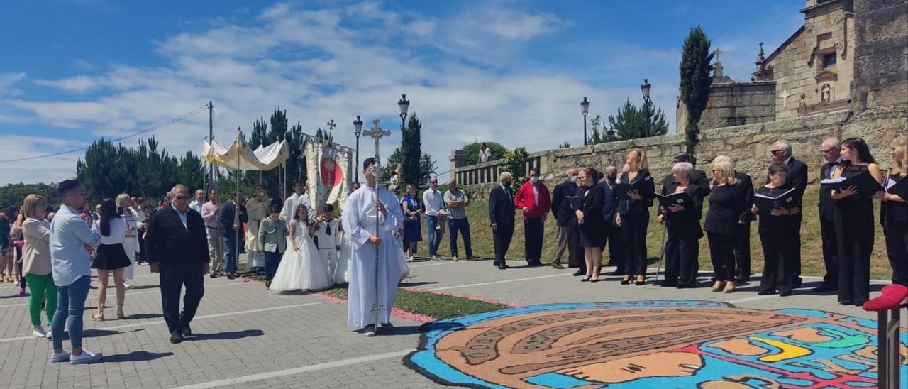 Un momento de la procesión, con algunos niños que hicieron su Primera Comunión y una de las alfombras de flores, en este caso reproduciendo la moneda de Adro Vello.