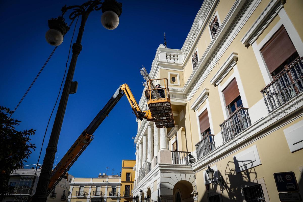 Un trabajador coloca el alumbrado navideño en la fachada del Ayuntamiento de Badajoz, este martes.