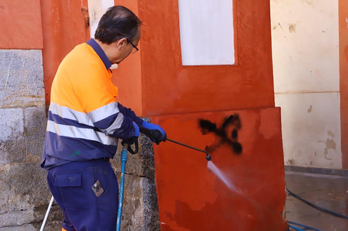 Un operario limpia una de las pintadas de la Corredera.