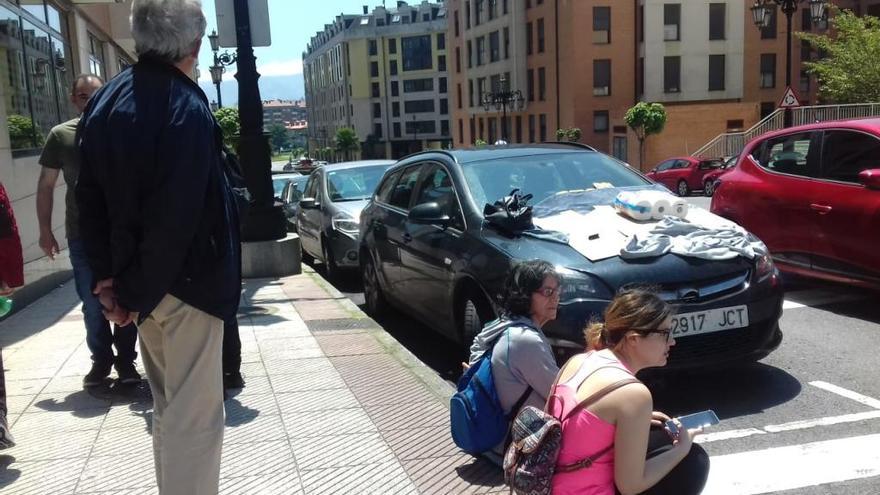 Varios vecinos tratan de salvar a un gato atrapado en el motor de un coche en Oviedo