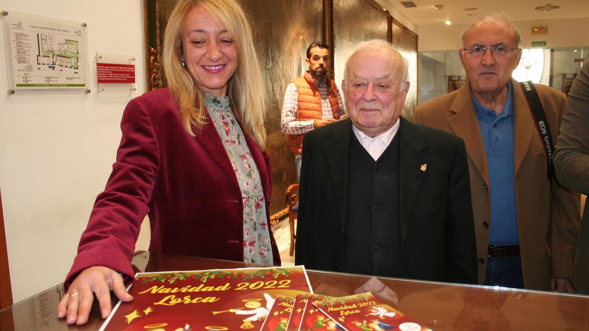 María Ángeles Mazuecos, Manuel Sevilla y José Antonio Ruiz, con el cartel y el programa de Navidad de los Belenistas.
