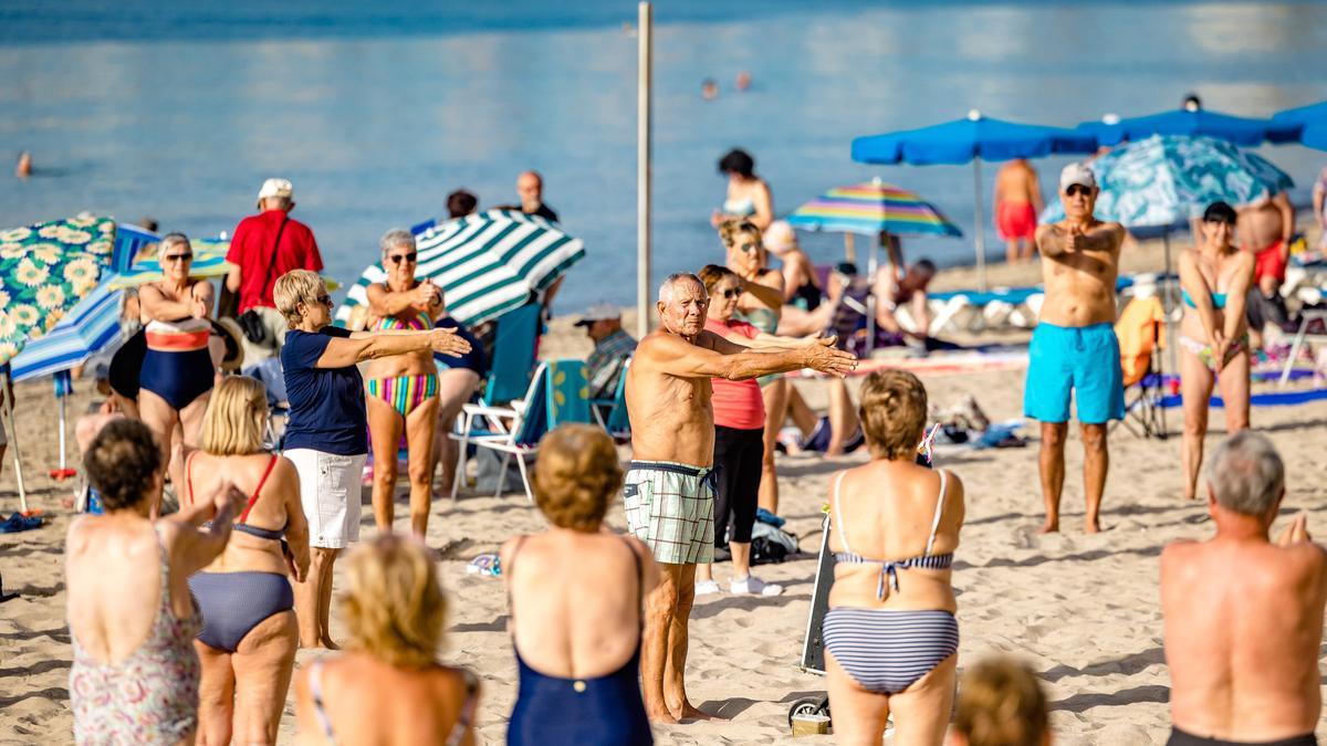 Un grupo de jubilados realiza ejercicio en la playa, en Benidorm.