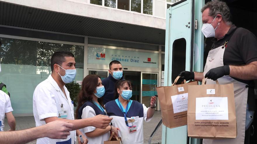 Varios sanitarios reciben unas bolsas con alimentos.