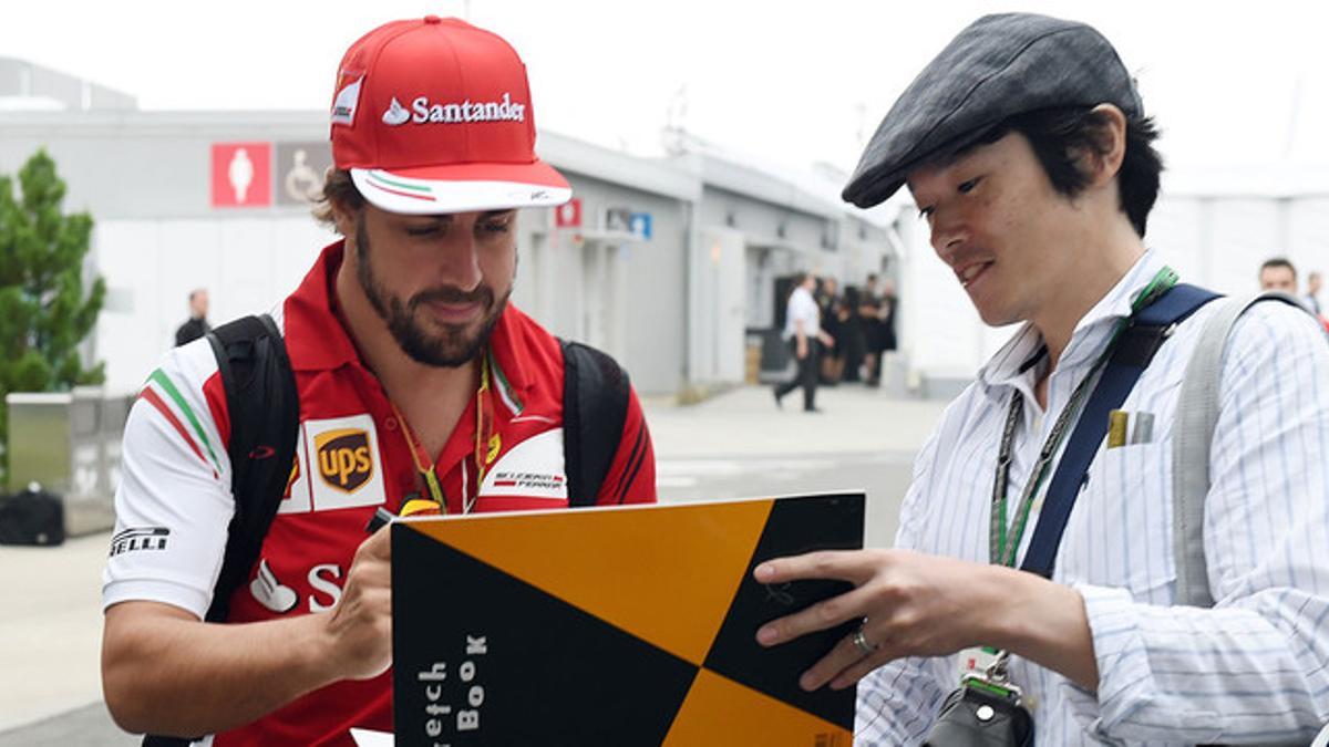 Fernando Alonso firma un autógrafo a un fan en el circuito de Suzuka