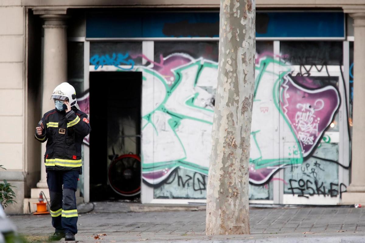 A firefighter speaks on phone outside premises burned down in Barcelona, Spain, 30 November 2021. Four people died, including two children, and four other were poisoned by smoke after a fire started on the premises where they were living at Tetuan Square, in Barcelona. EFE/Marta Perez