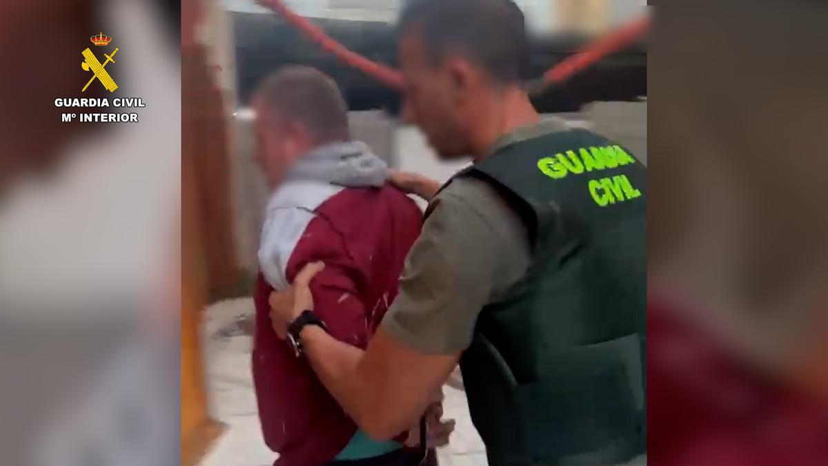 Un agente de la Guardia Civil traslada a uno de los detenidos.