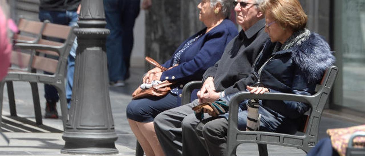 Jubilados canarios descansan en un banco.