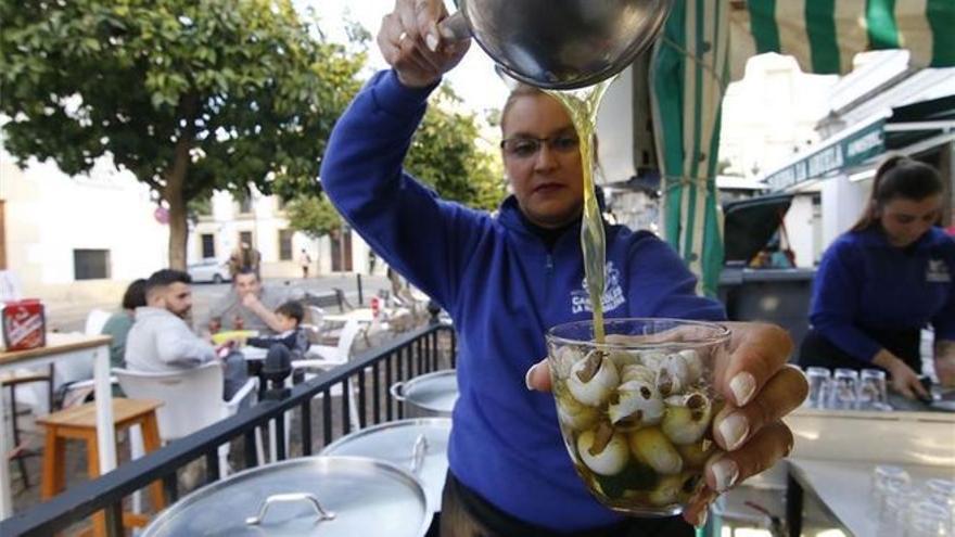 Una mujer sirve una taza de caracoles en Córdoba.