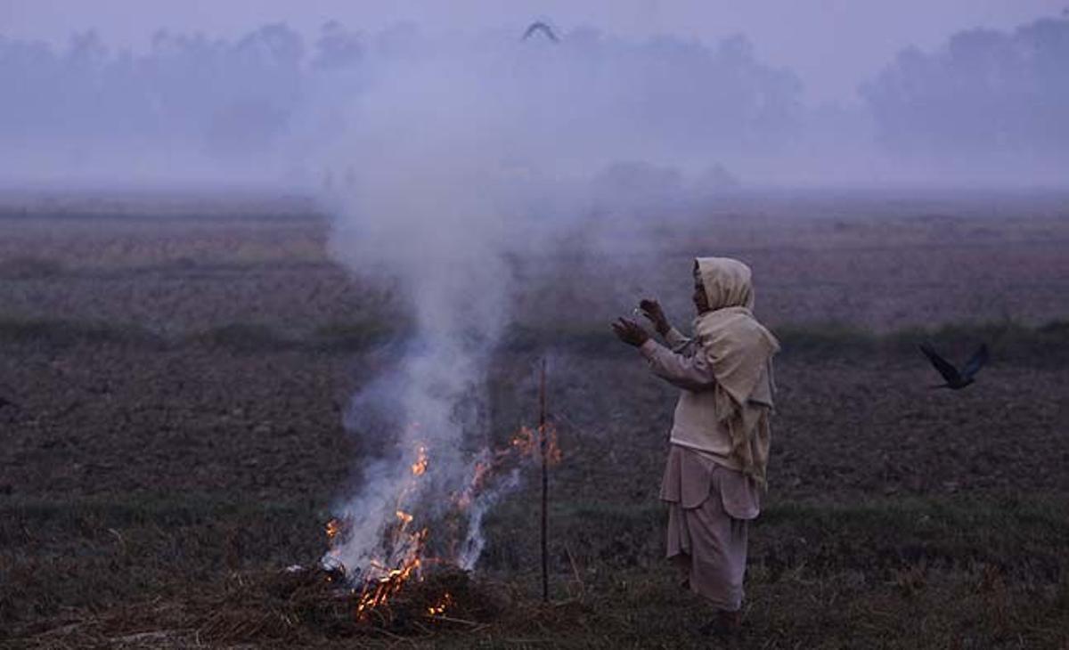 Un agricultor s’escalfa a prop del foc per evitar el fred del matí a Jammu (Índia).
