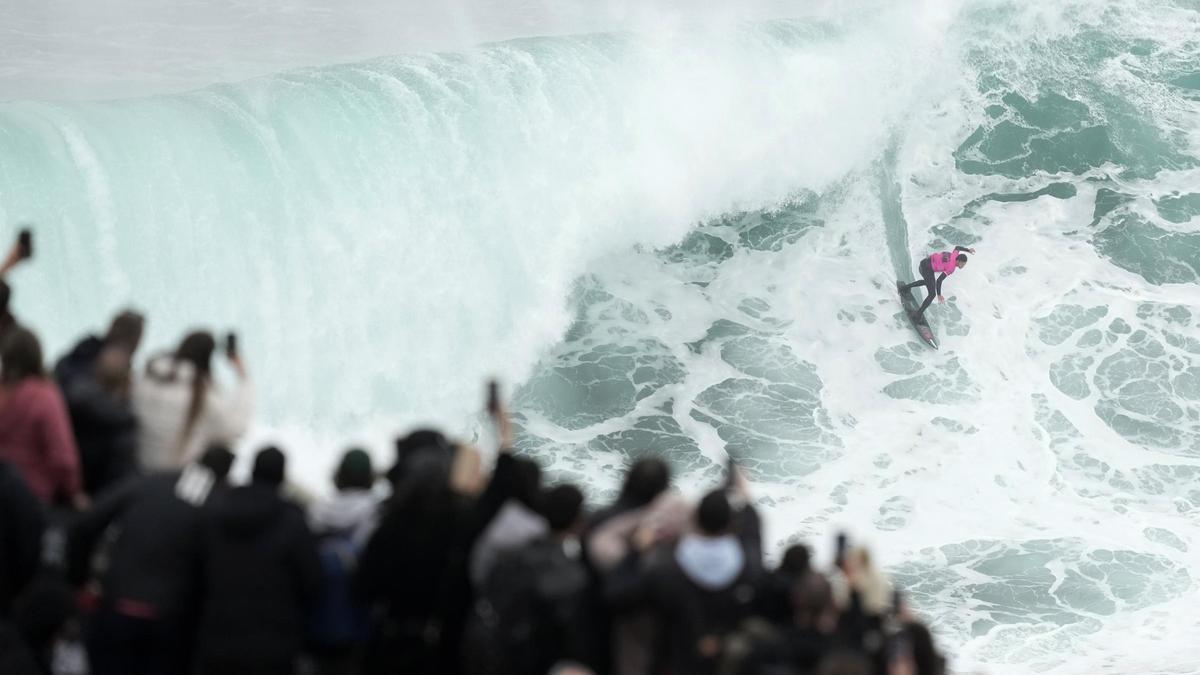 Un surfista desafia una onada davant desenes d'espectadors