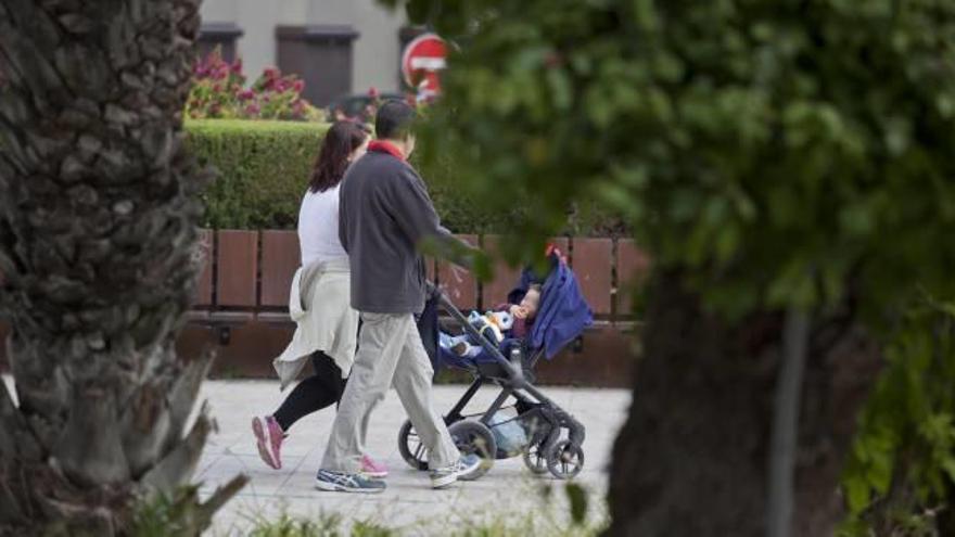 Una pareja con un recién nacido paseando por una calle céntrica de Elche.