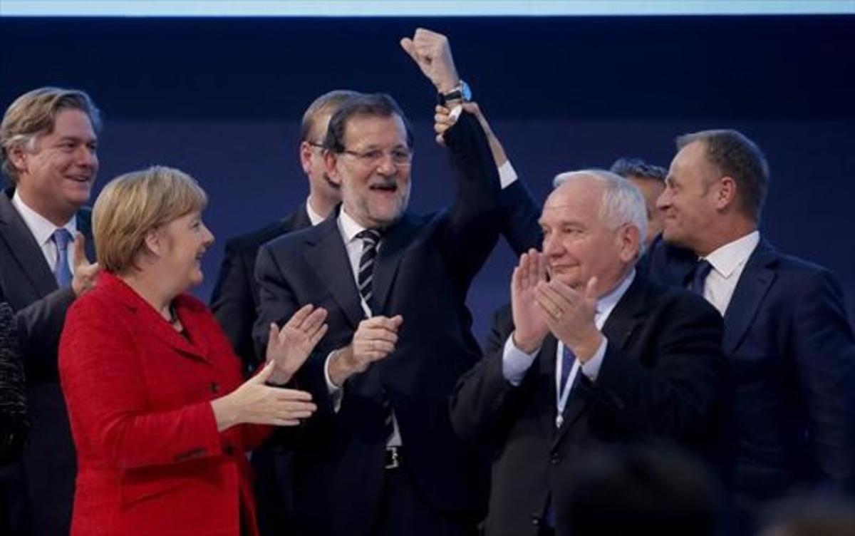 El president del Consell Europeu, Donald Tusk, aixeca el braç de Rajoy en presència d’Angela Merkel i altres dirigents populars europeus.