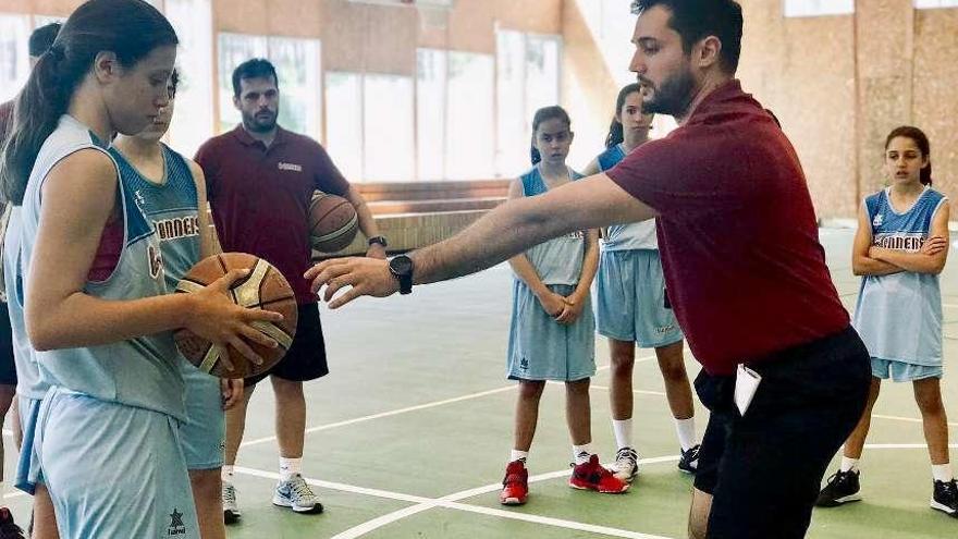 Una niña con un balón en la mano recibe las indicaciones de uno de los monitores. // FdV