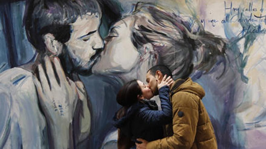 Una pareja se besa ante el mural de la calle Moret, ayer por la tarde.