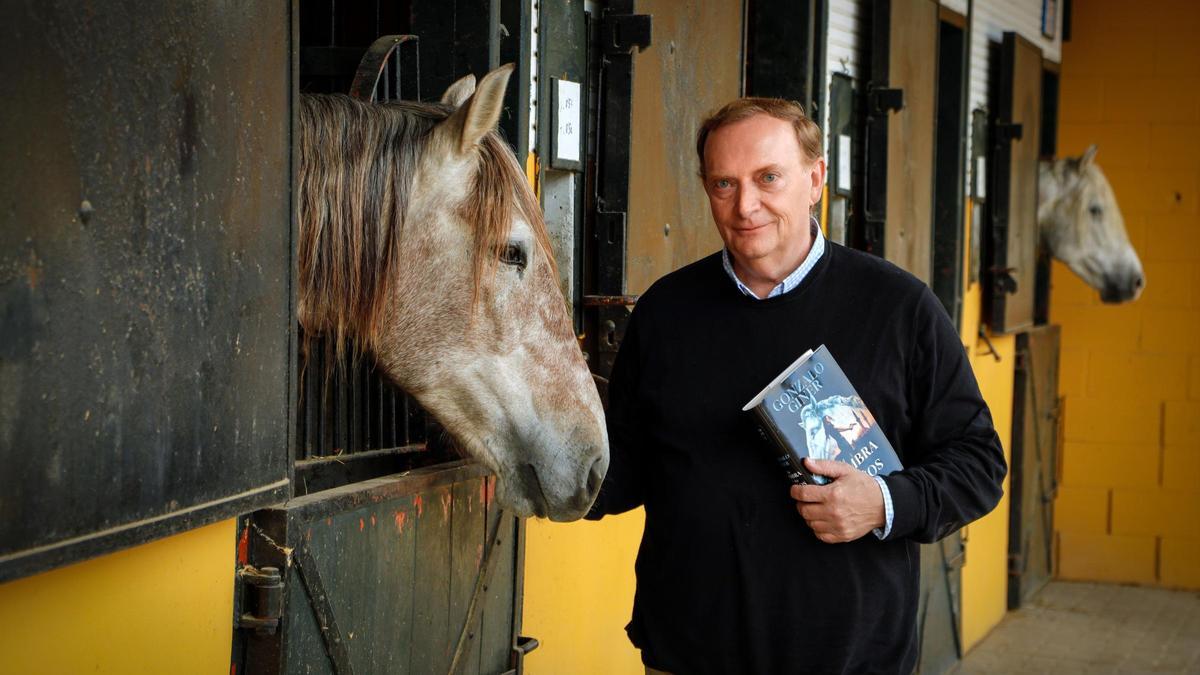 Gonzalo Giner con su libro, junto a un caballo, en la Yeguada La Cartuja