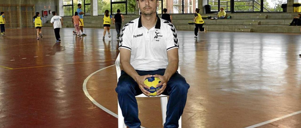 Juan Carlos Mena posa sentado en la pista del pabellón del Secar de la Real en el transcurso de un entrenamiento de la escuela de balonmano.