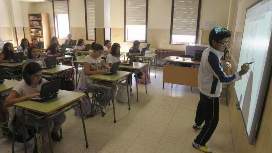 Alumnos de un centro gallego en una clase con ordenadores y pizarra digital. // FdV