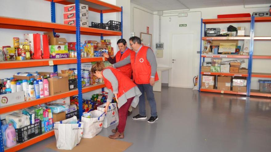 La responsable del programa y dos voluntarios revisan los enseres en el almacén de Cruz Roja.