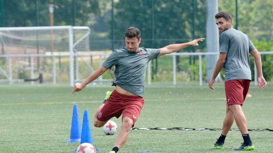 Kevin Presa practica disparos a puerta durante un entrenamiento ante la mirada de Churre. // Rafa Vázquez