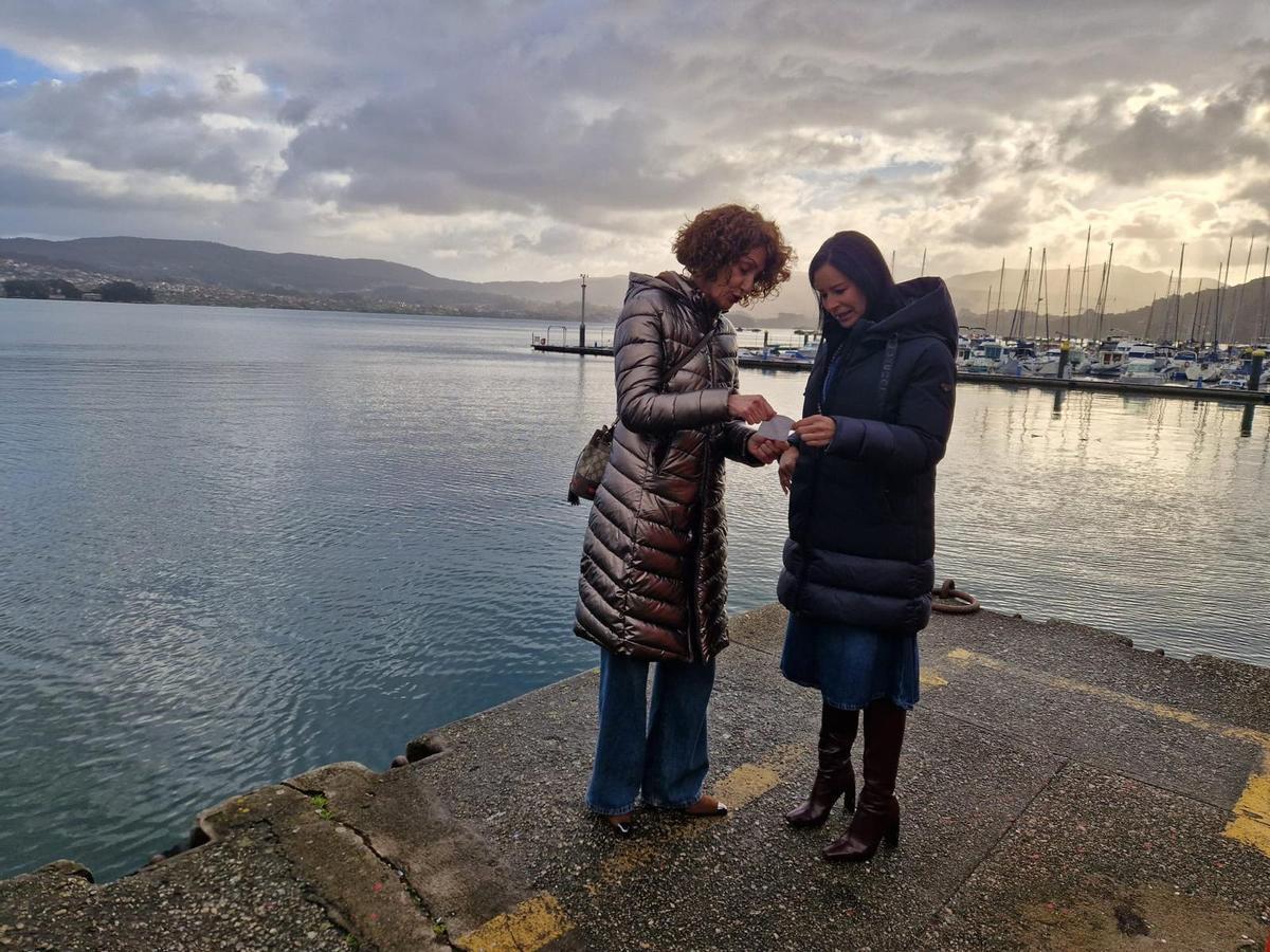 Loli Hermelo y Patricia García, observando un billete del transporte marítimo de ría.