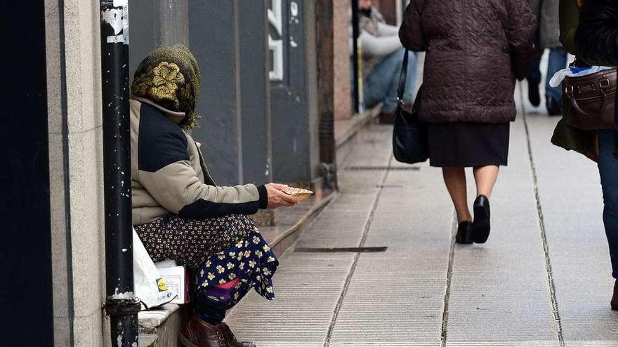 Una mujer pide limosna a las puertas de un supermercado gallego.