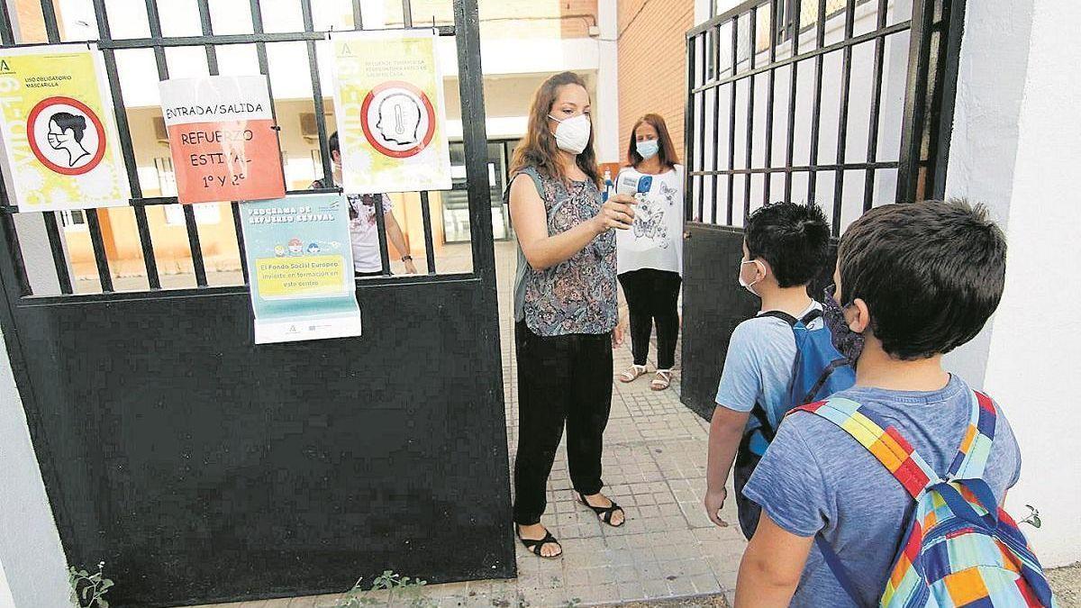 Una mujer toma la temperatura a un niño a su entrada al colegio.